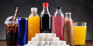 Suikerrijke drankjes en gewichtstoename Glas frisdrank met suikerklontjes ernaast, visuele vergelijking van suikergehalte en impact op dagelijkse calorie-inname
